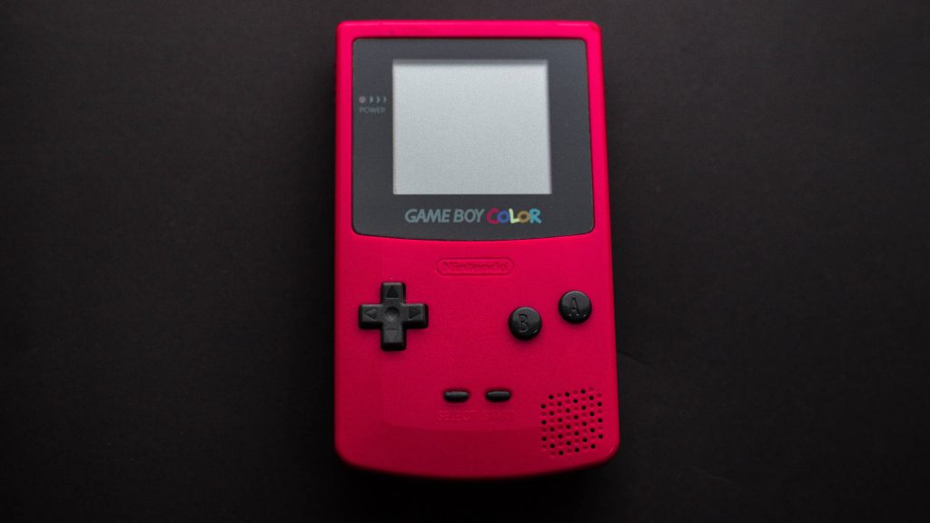 Minimalist red Nintendo Game Boy Color handheld console top view on black background gaming device Wallpaper