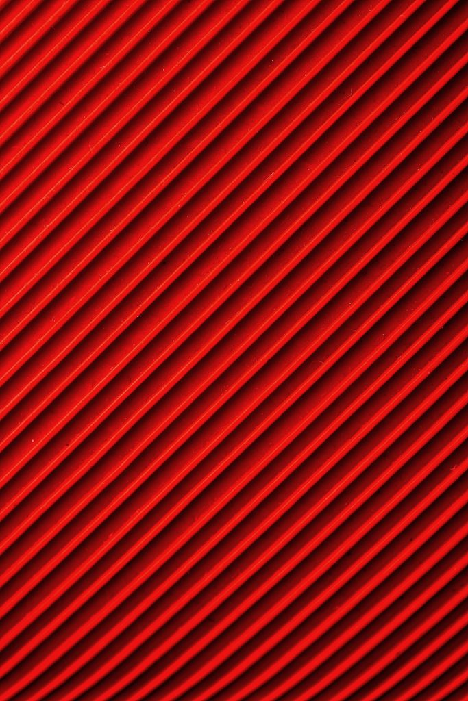 Minimalist 4K wallpaper with vibrant red diagonal ribbed texture for sleek modern backgrounds