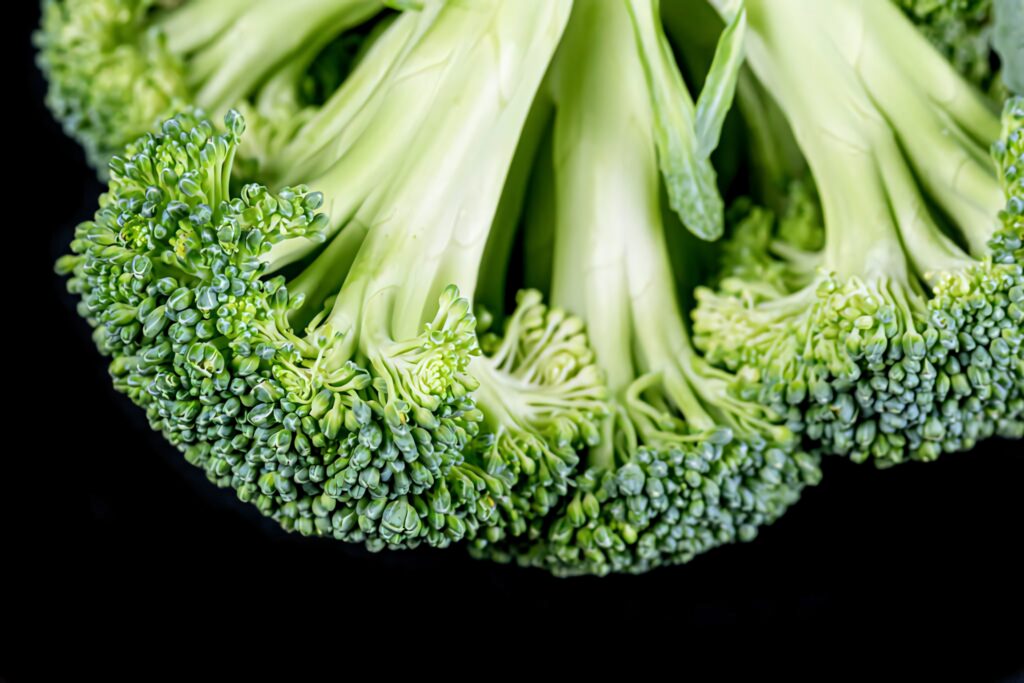 Minimalist reversed broccoli close up with vibrant green florets on sleek black background wallpaper