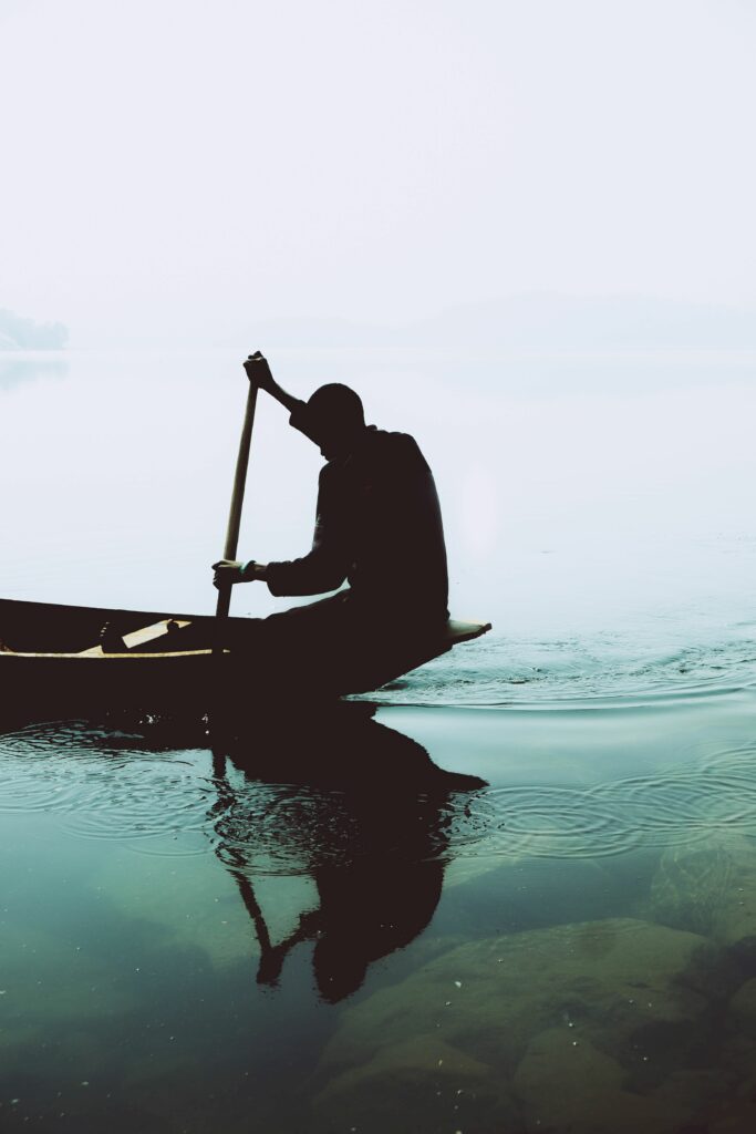 Minimalist wallpaper silhouette lone paddler on calm water with soft tones and gentle ripples