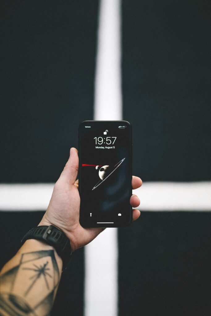 Minimalist Tattooed Hand Holding Smartphone Wallpaper Background