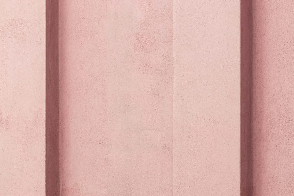 Minimalist soft pink wallpaper with vertical geometric panels and textured matte surface design