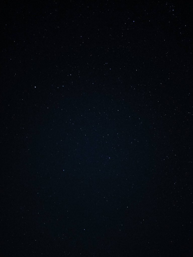 Minimalist starry night sky wallpaper with deep black background and distant sparkling stars