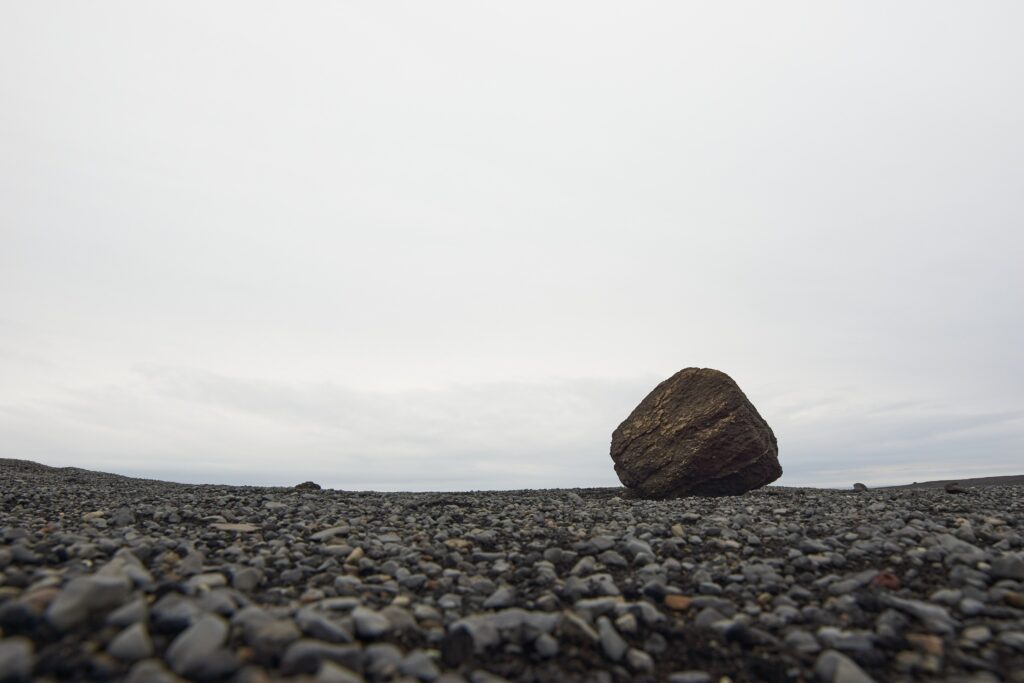 Minimalist stone block on pebbled ground under overcast sky calm natural landscape wallpaper