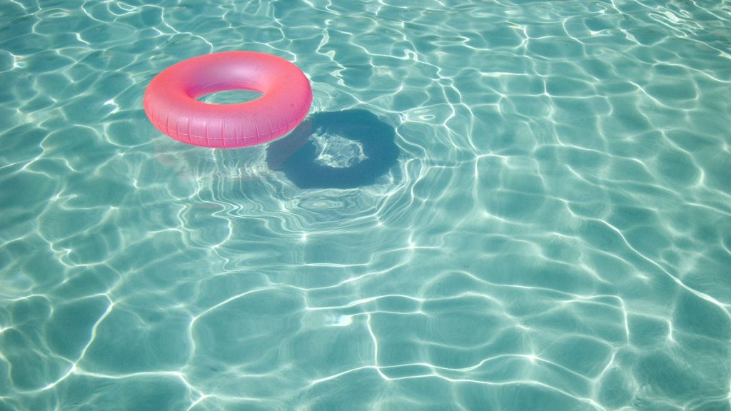 Minimalist summer laptop wallpaper pink floatie in turquoise pool with sunlit shimmering water patterns