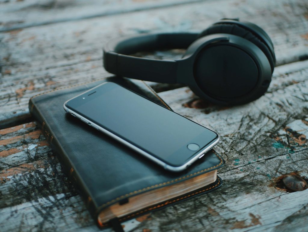Sleek smartphone on leather notebook with black headphones on weathered wood table background Wallpaper