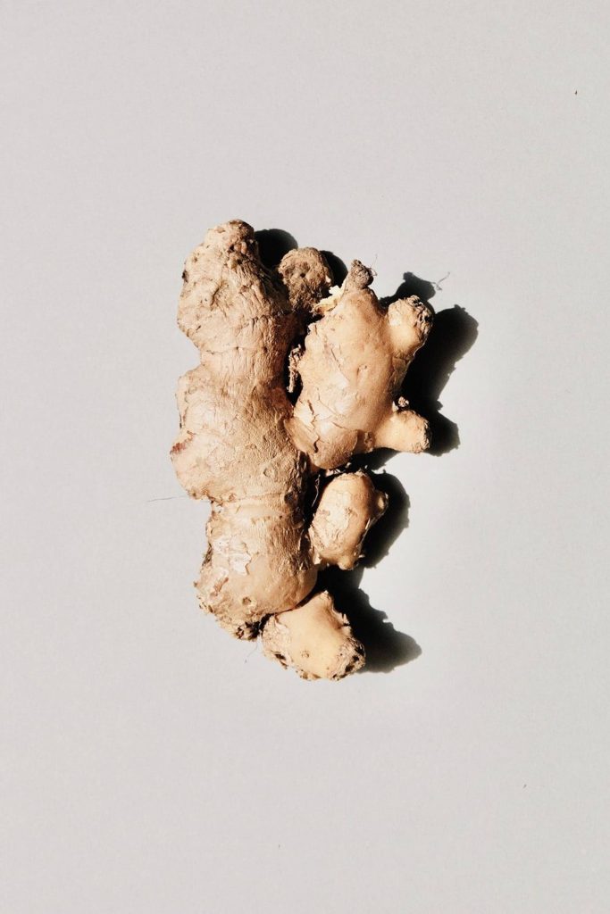 Top-down fresh ginger rhizome with sharp side lighting on neutral background high quality wallpaper