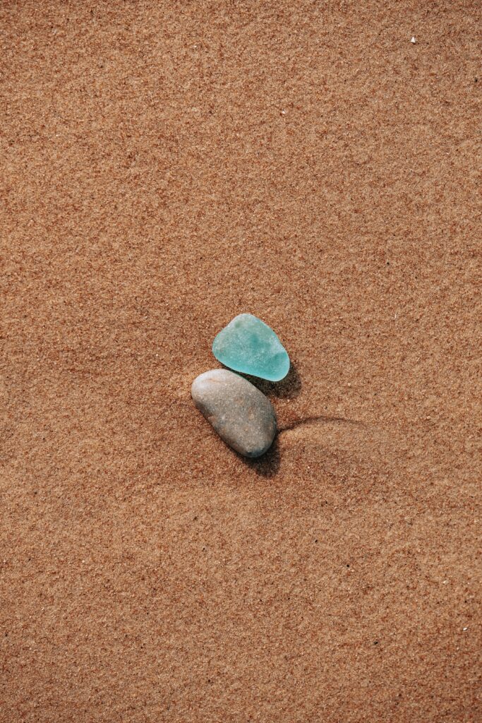 Minimalist Wallpaper: Blue-Green & Gray Pebbles on Sandy Surface