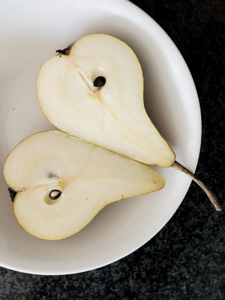 Minimalist Wallpaper: Fresh Pear Halves on White Plate, Dark Surface