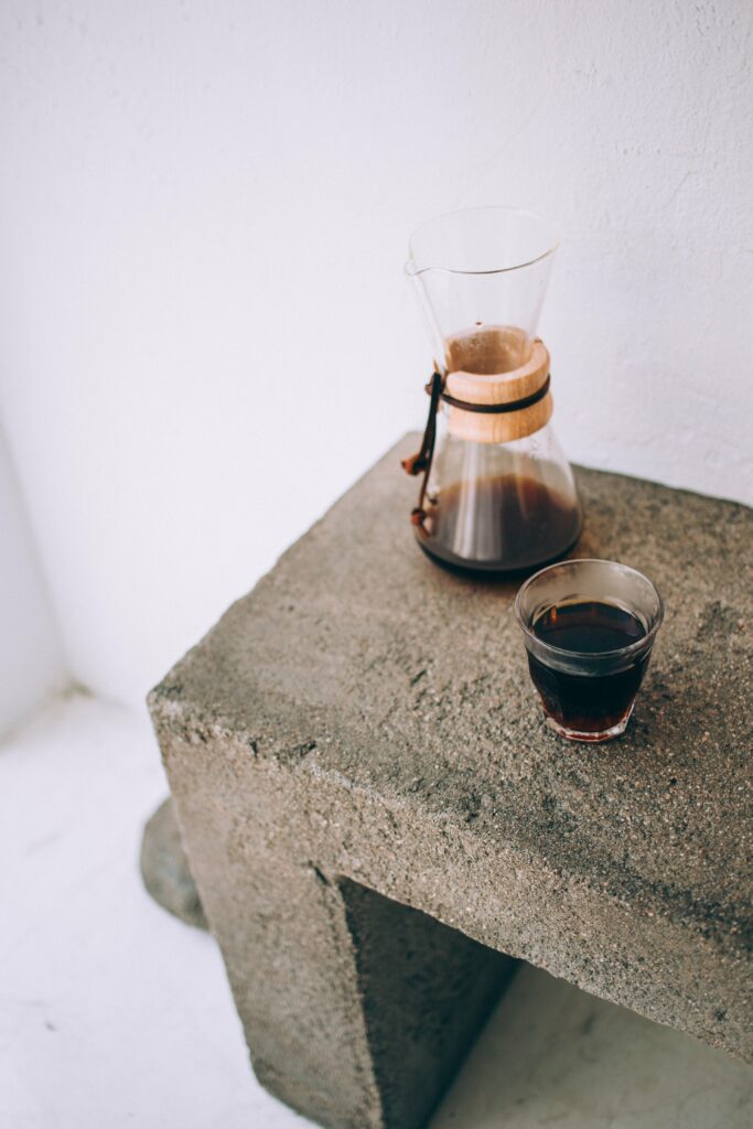 Minimalist Wallpaper: Glass Carafe & Coffee Cup on Rustic Concrete