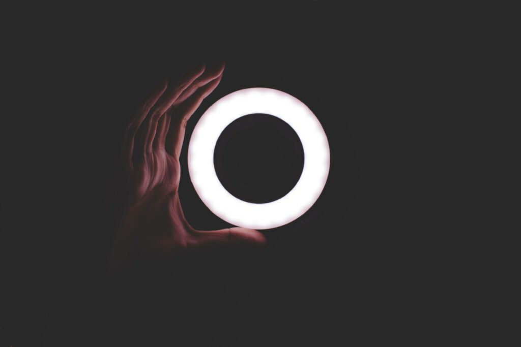 Minimalist Wallpaper: Glowing LED Ring Light Handheld on Dark Background