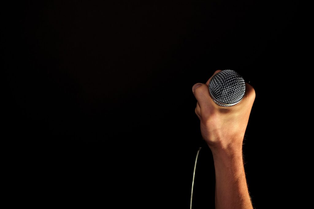 Minimalist Wallpaper: Hand Gripping Microphone on Black Background