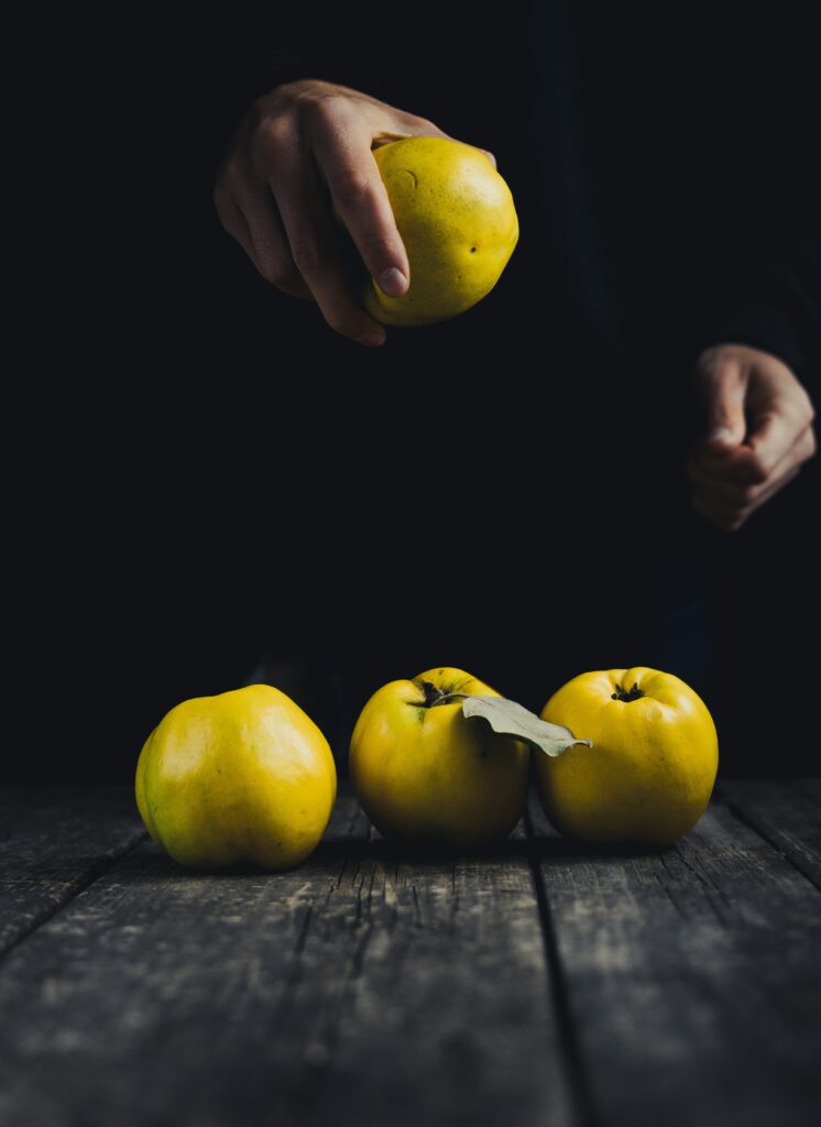 Minimalist Wallpaper: Hand Holding Yellow Apple on Rustic Wood