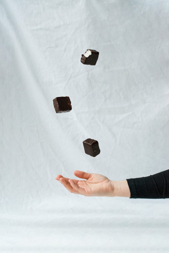 Indulgent Minimalist Wallpaper: Hand Reaching for Dropping Chocolate