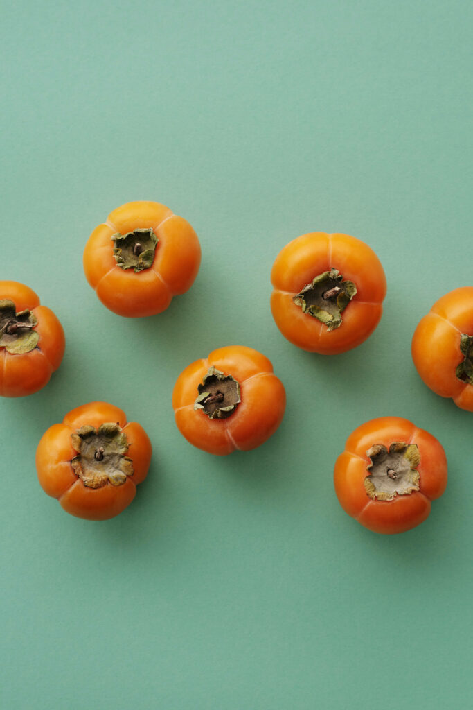 Modern Minimalist Wallpaper: Seven Persimmons on Green Background