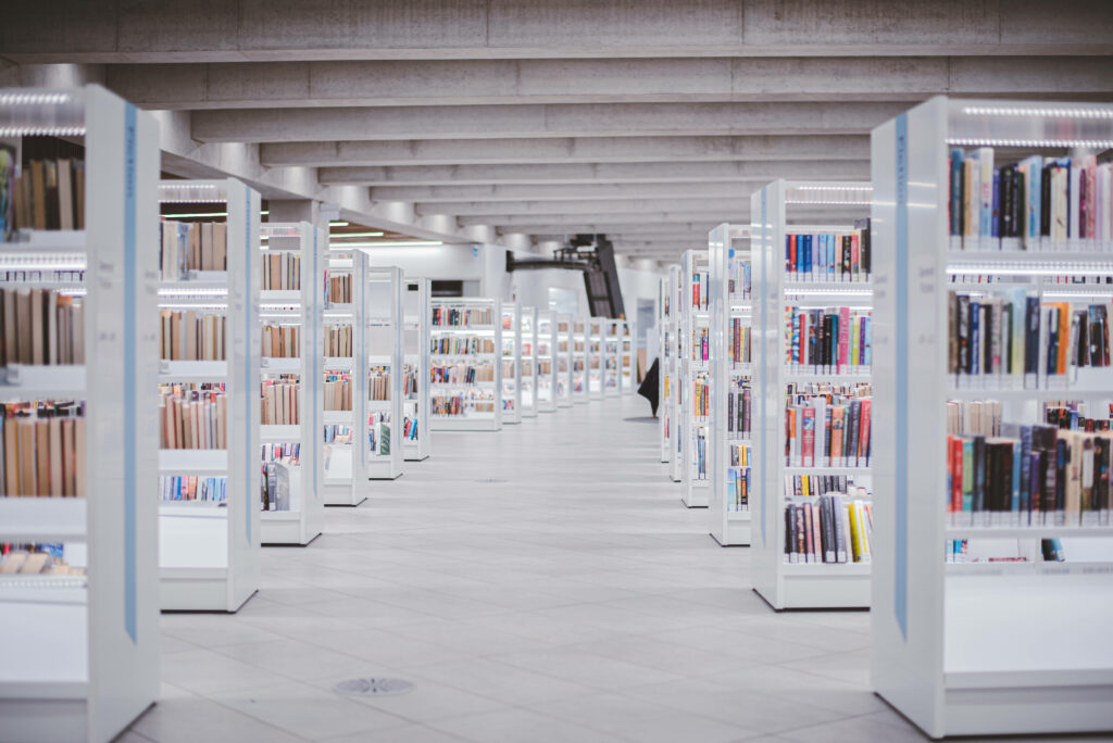 Minimalist bright library with sleek white shelves filled with colorful books elegant modern design Wallpaper