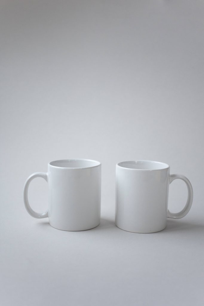 Two classic white ceramic mugs side by side on neutral grey background minimalist photo wallpaper