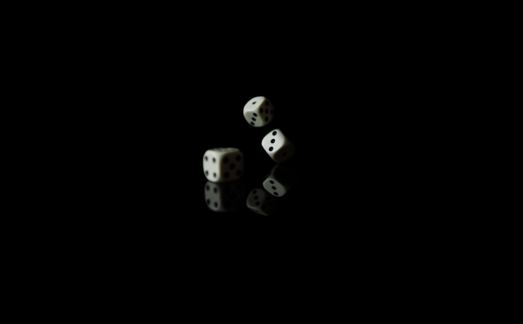 Three white dice suspended against black background highlighting chance risk minimalist design Wallpaper