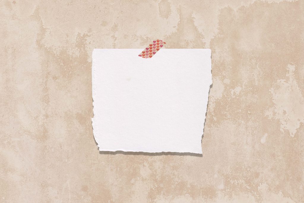 Minimalist white torn paper note on rustic beige wall with heart washi tape romantic wallpaper