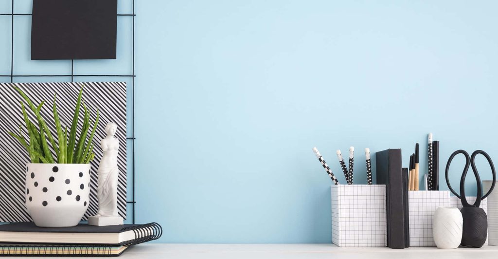 Minimalist workspace Zoom background with light blue wall plant classical figurine notebooks pens Wallpaper