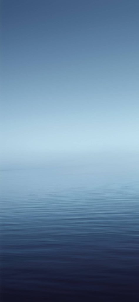 Minimalist iOS wallpaper with serene deep ocean blue gradient and soft hazy sky background