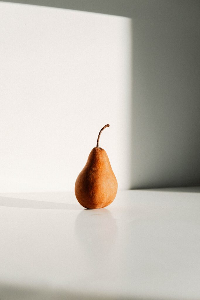 Minimalist Brown Pear Wallpaper on Light Background with Soft Shadows