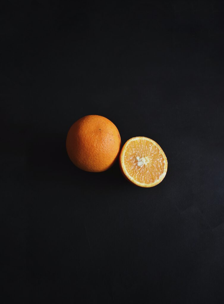 Minimalistic Orange Wallpaper: Whole & Sliced Citrus on Dark Background