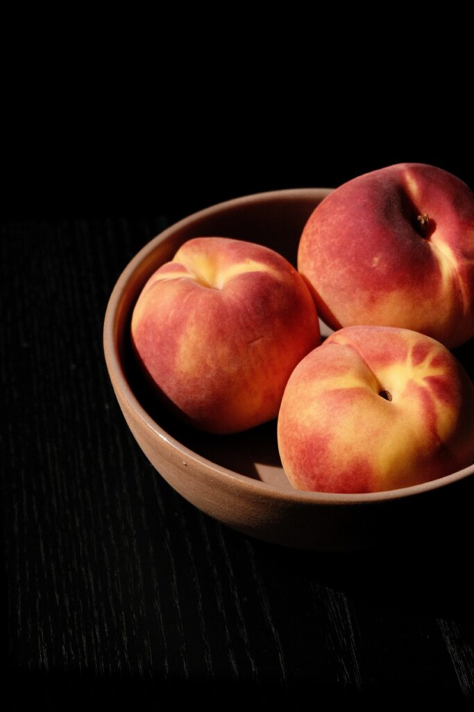 Minimalist Wallpaper: Ripe Peaches in Rustic Bowl on Dark Table