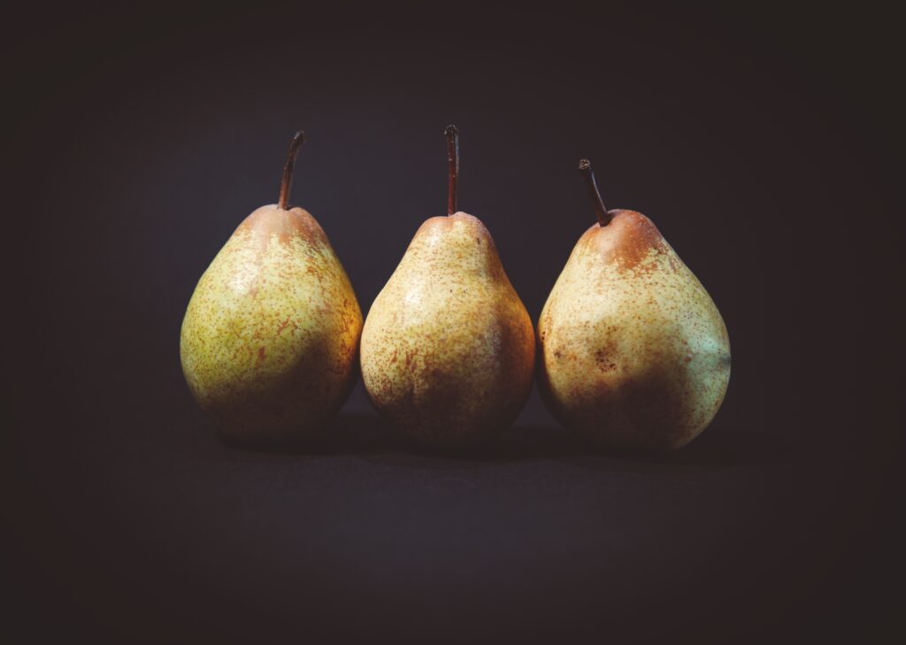 Minimalistic Wallpaper: Three Ripe Pears on Dark Background