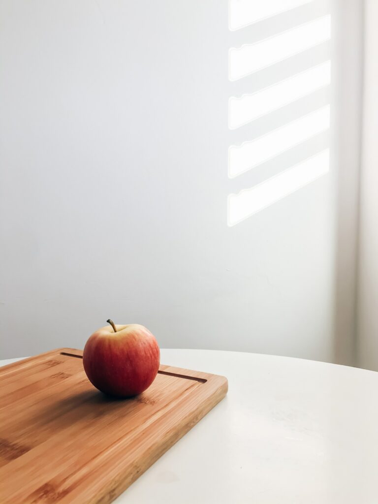Minimalistic Red Apple Wallpaper on Wooden Board with Soft Light