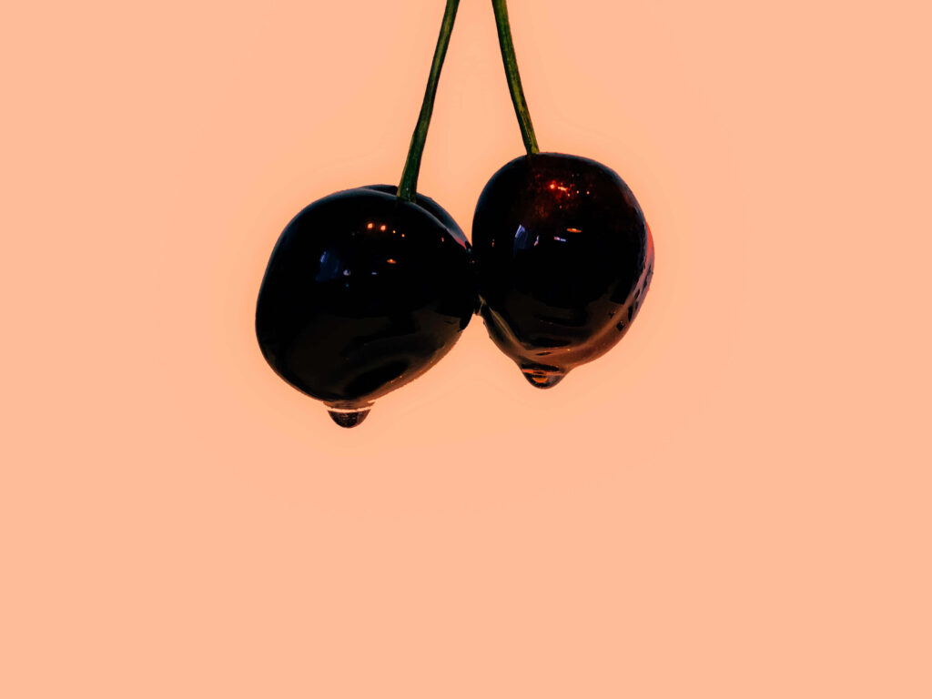 Minimalist Cherry Wallpaper: Glossy Cherries on Soft Peach Background