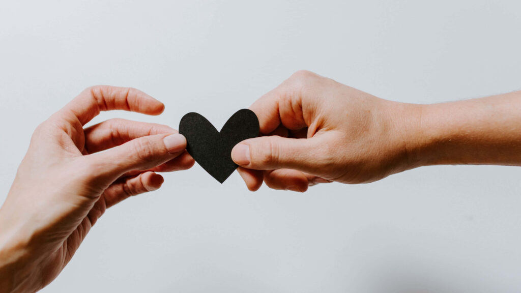 Minimalistic Wallpaper: Two Hands Holding a Black Heart Symbolizing Love