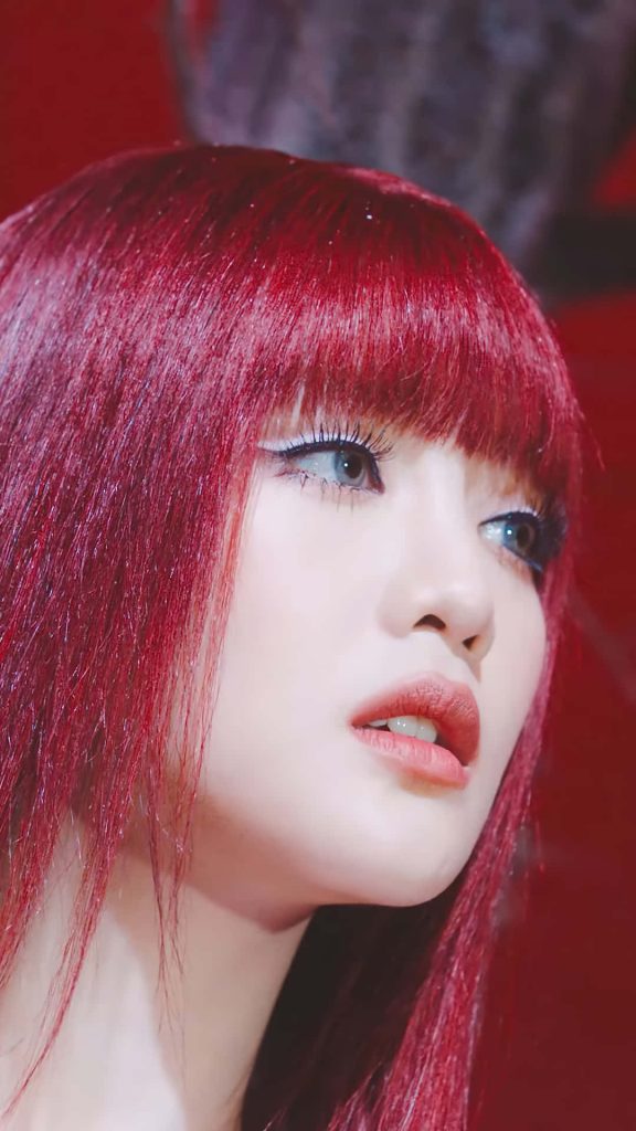 Close-up portrait of Minnie from G I DLE with vibrant red hair and sharp winged eyeliner wallpaper