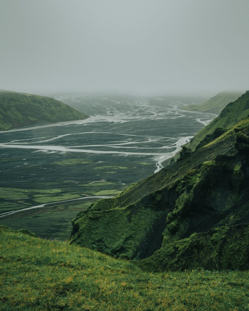 Aerial view of misty green valley with winding rivers and dramatic natural landscape wallpaper