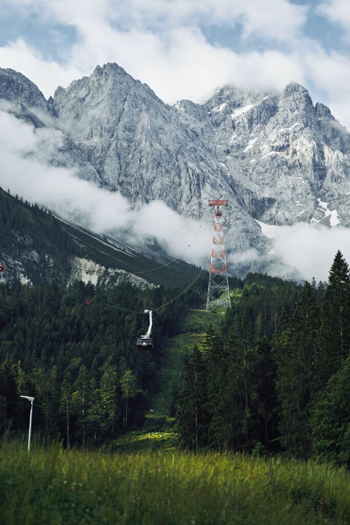 Rugged misty mountains with evergreen trees and cable car in serene alpine landscape wallpaper
