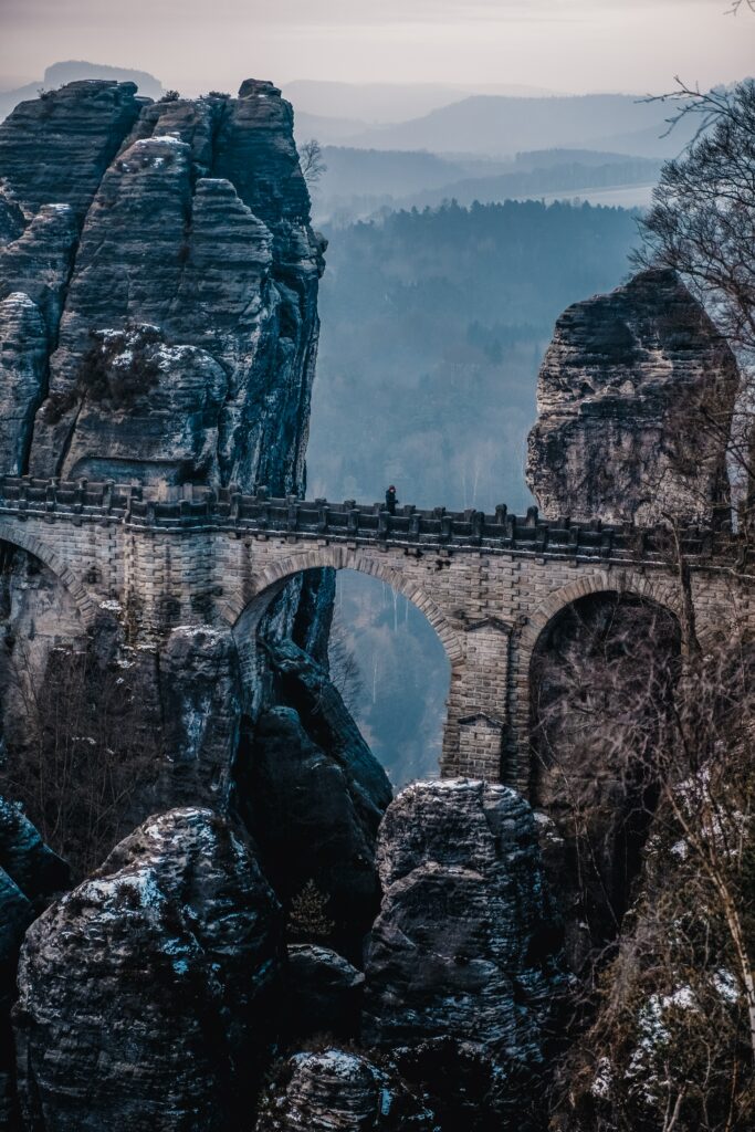 Bastei Bridge in misty German mountains with towering rocks and cool blue grey tones wallpaper