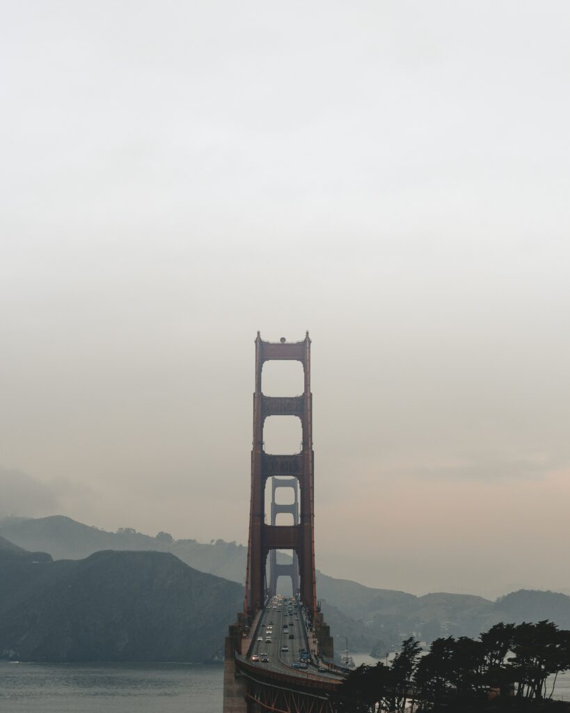 Tall bridge over calm coastal foggy landscape with majestic mountains serene wallpaper background