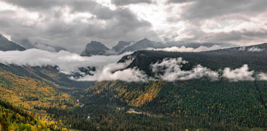 Misty forested mountains with rolling clouds under moody sky nature landscape wallpaper background