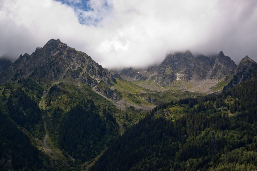 Breathtaking mountain landscape with misty jagged peaks dense evergreen forests and rolling clouds Wallpaper