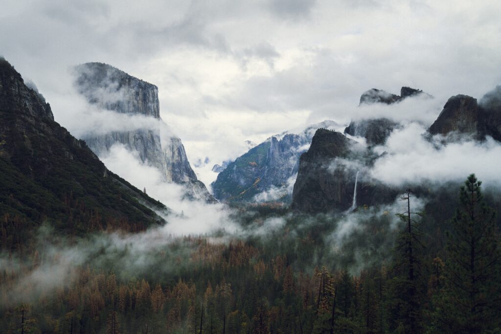 Breathtaking mountain landscape with rocky cliffs forests misty valleys and dramatic clouds wallpaper