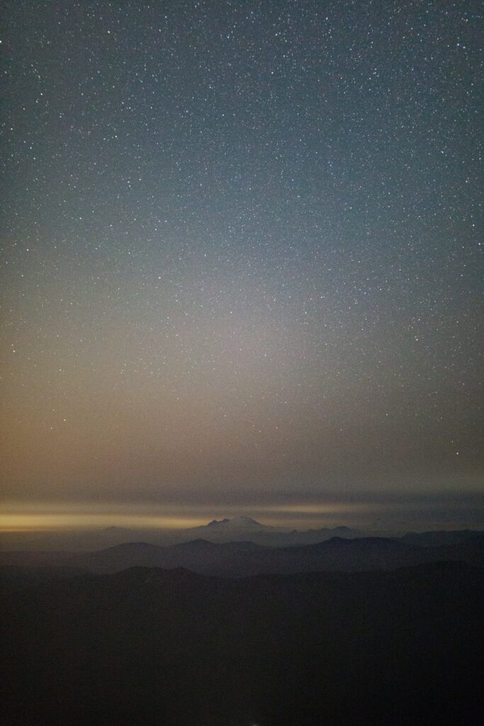 Aerial view of misty mountains under starry night sky with layered fog and soft cosmic light Wallpaper