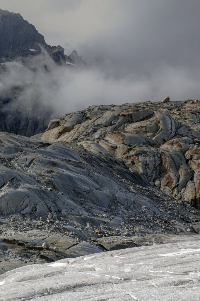 Rugged stone formations with textured relief and foggy mountainous background wallpaper