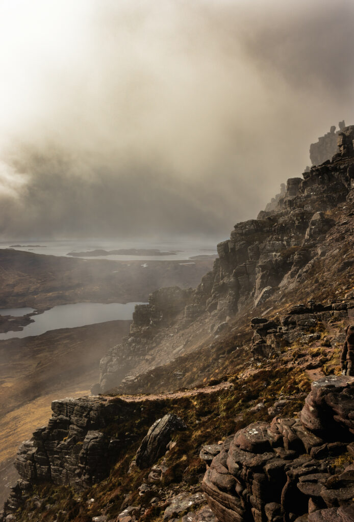 Misty rugged stone cliffs over foggy valley with textured rocks and earthy brown-gray tones wallpaper