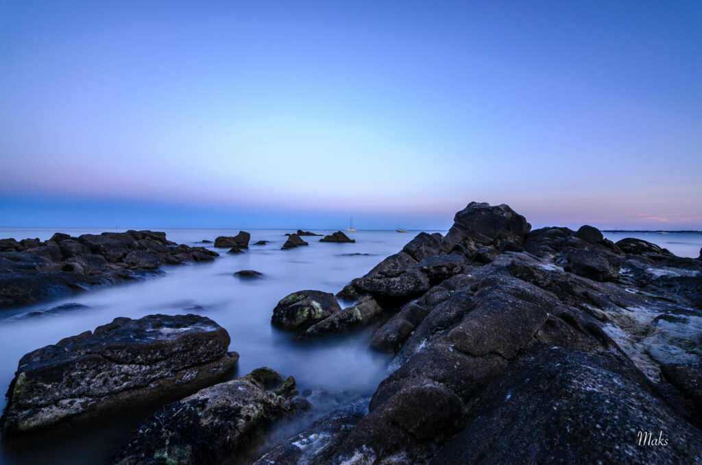 Tranquil seascape with rugged stones misty fog calm water serene blue sky peaceful scene wallpaper