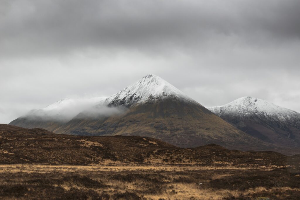 Snow-capped mountain peaks with mist and clouds over rugged terrain serene winter landscape wallpaper