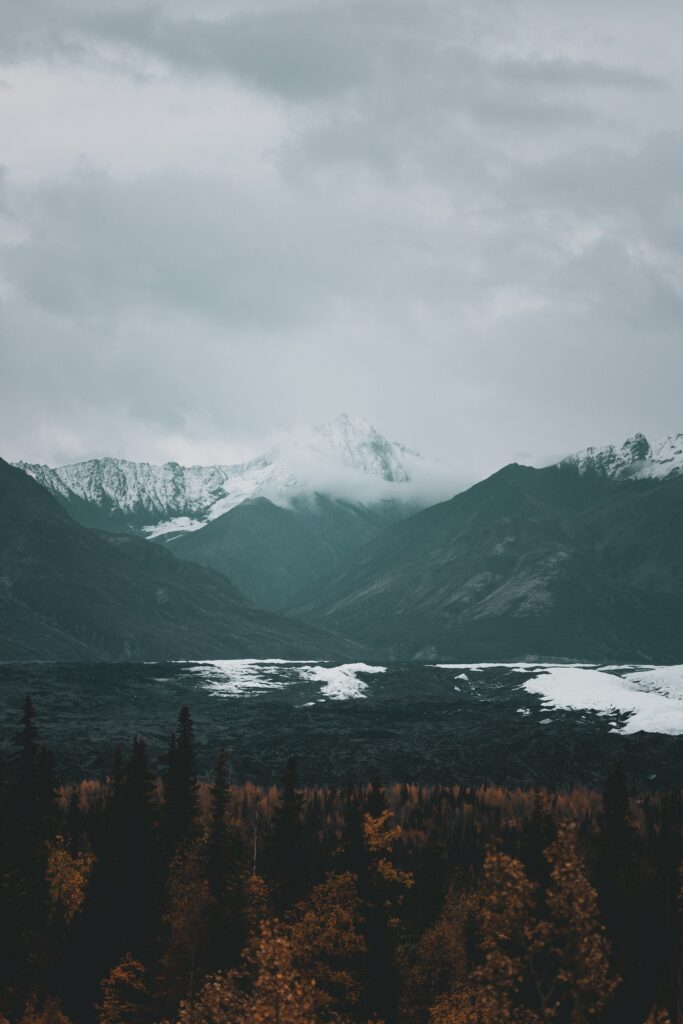 Snowy mountain peaks with mist over dark forest and autumn colors tranquil landscape wallpaper