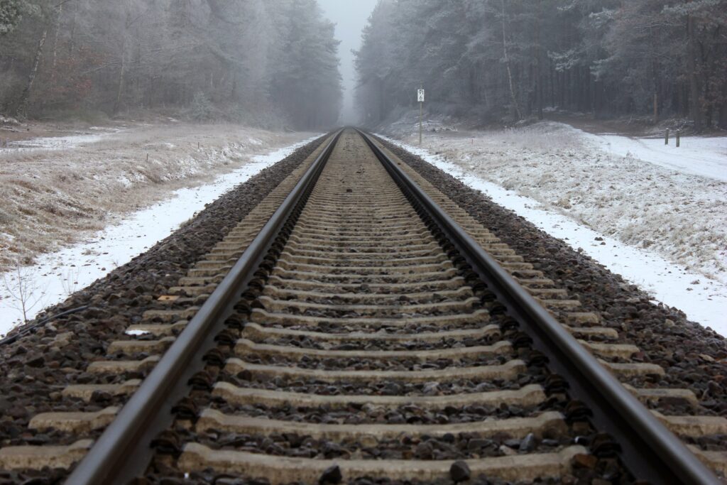 Railway track fading into foggy snow-covered forest winter landscape background wallpaper