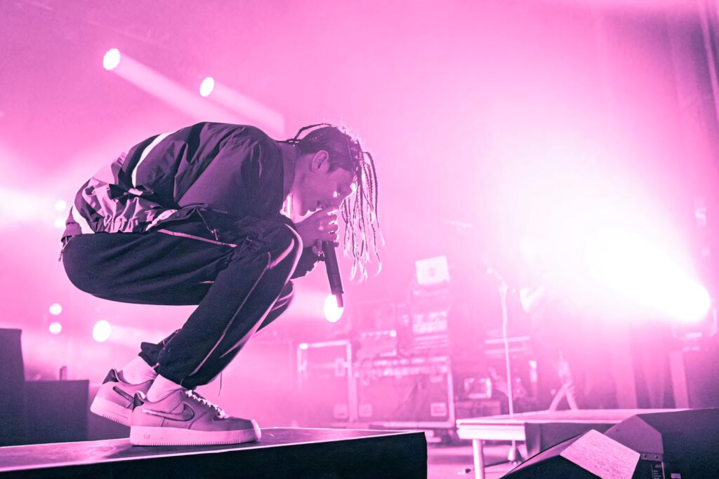 Mitchel Cave of Chase Atlantic performing live on stage with vibrant pink and purple lighting Wallpaper