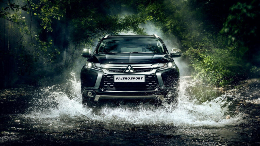Mitsubishi Pajero Sport SUV crossing shallow forest stream showcasing rugged power and design Wallpaper