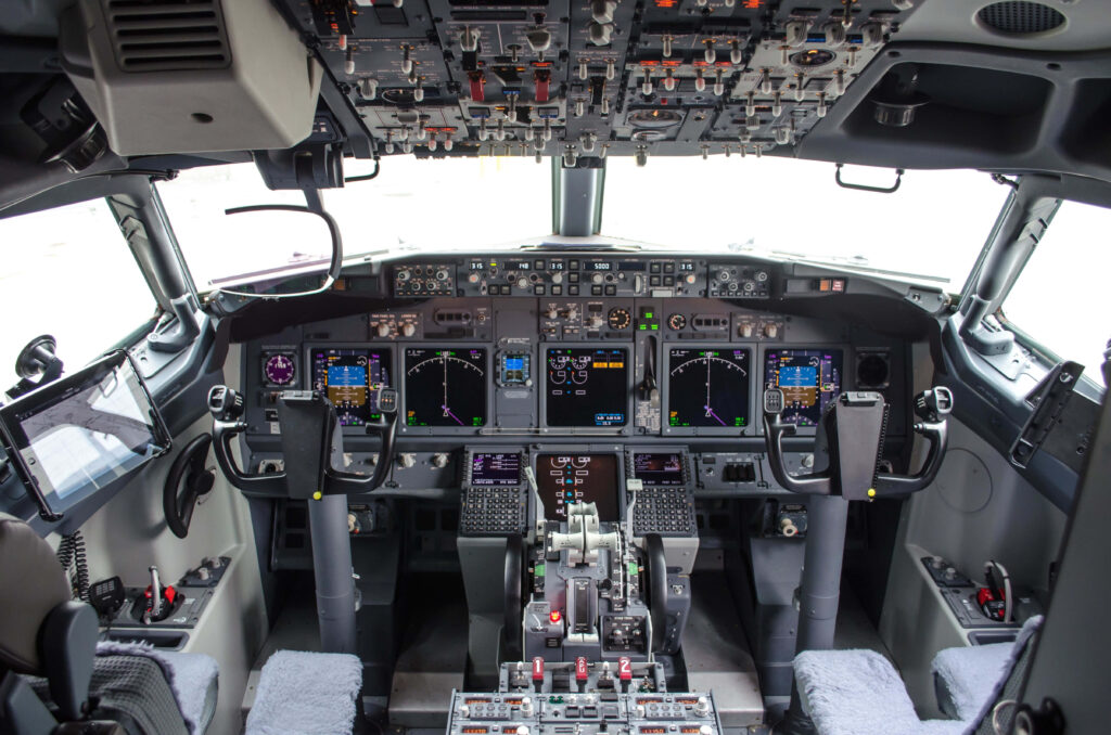 Modern airliner cockpit with advanced digital displays illuminated panels and dual control columns Wallpaper